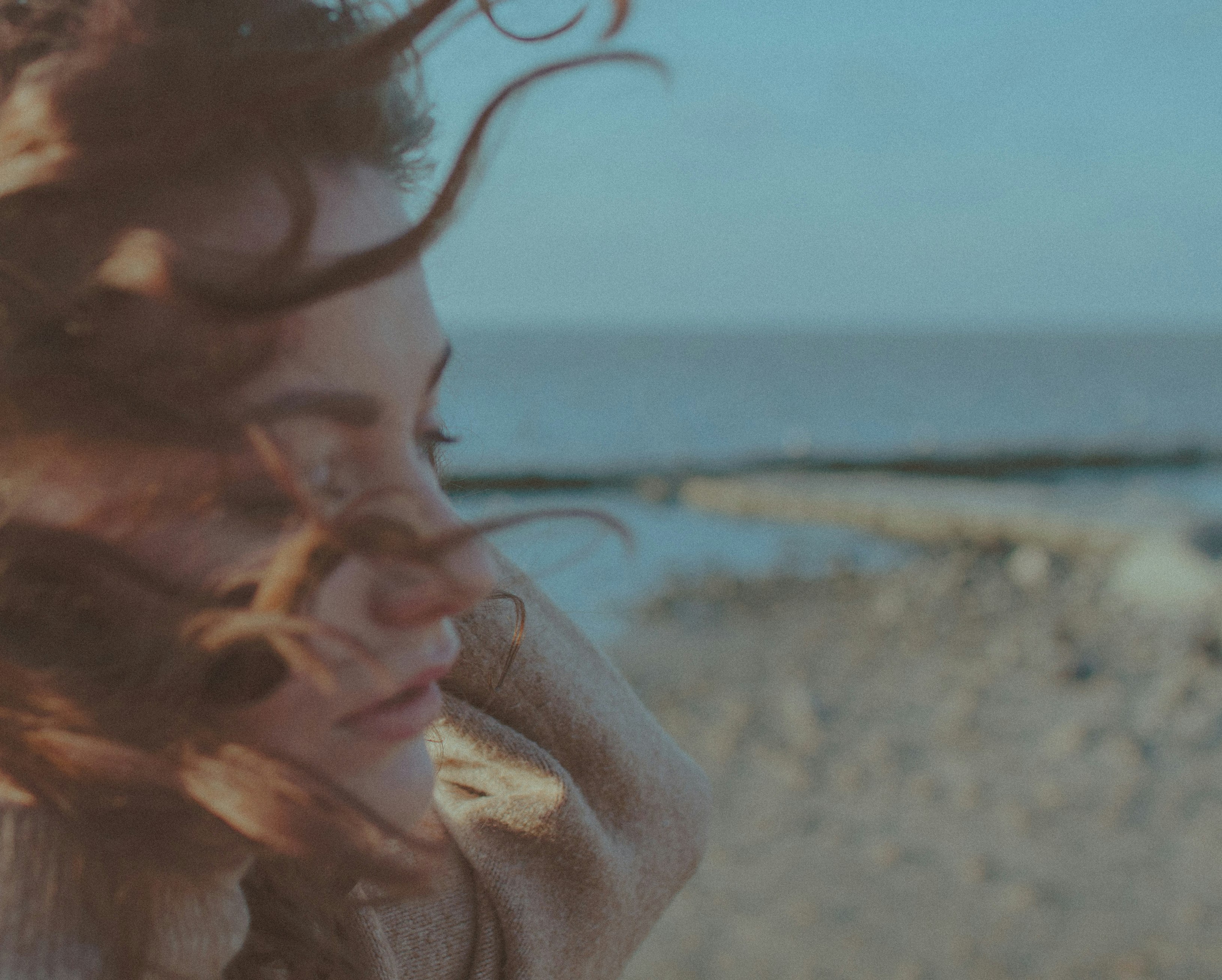 woman in white hoodie standing on beach shore during daytime